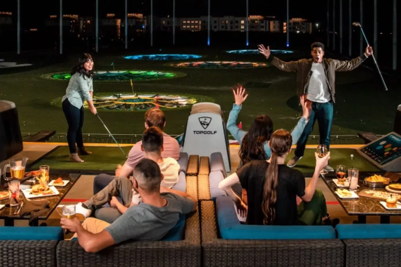 Gäste feiern in einer Topgolf-Bay bei Nacht